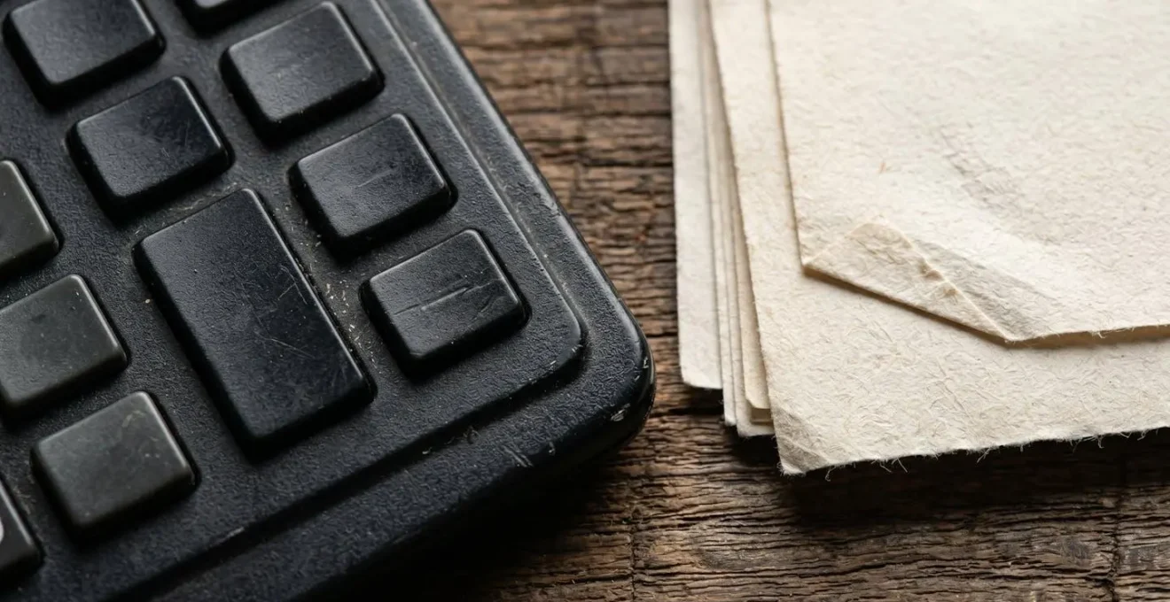 Bureau avec calculatrice et documents fiscaux étalés pour le calcul des déductions successorales